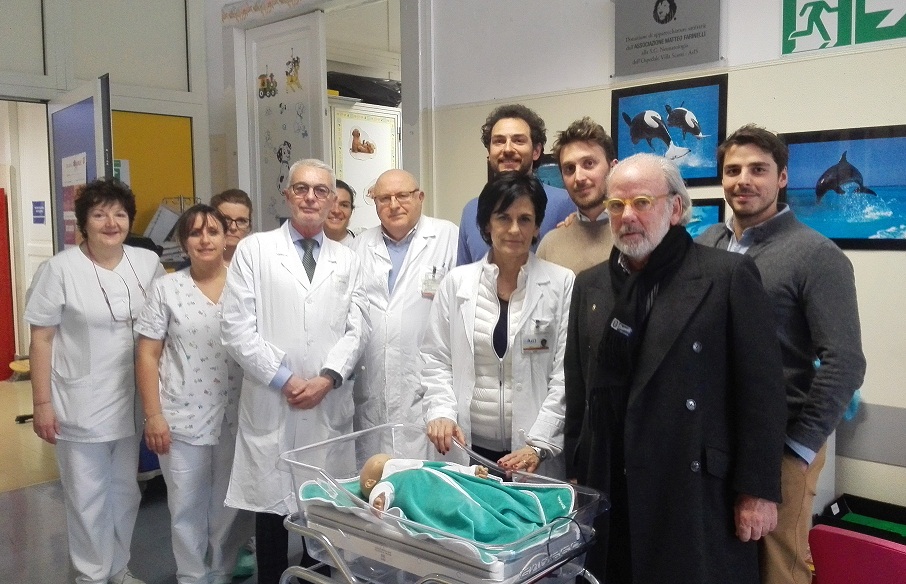 i rappresentanti dell'associazione Matteo Farinelli insieme all'equipe della Neonatologia - diretta dal dott. Stefano Macciò - e al direttore sanitario di Asl3 Marta Caltabellotta fotografati con con uno dei presidi donati al reparto, utile nei casi di ittero neonatale (nella foto con bambolotto per simulazione). Le altre attrezzature donate sono una sonda ecografo e un manichino utilizzato per attività di precisione nell’ambito di corsi di aggiornamento. 